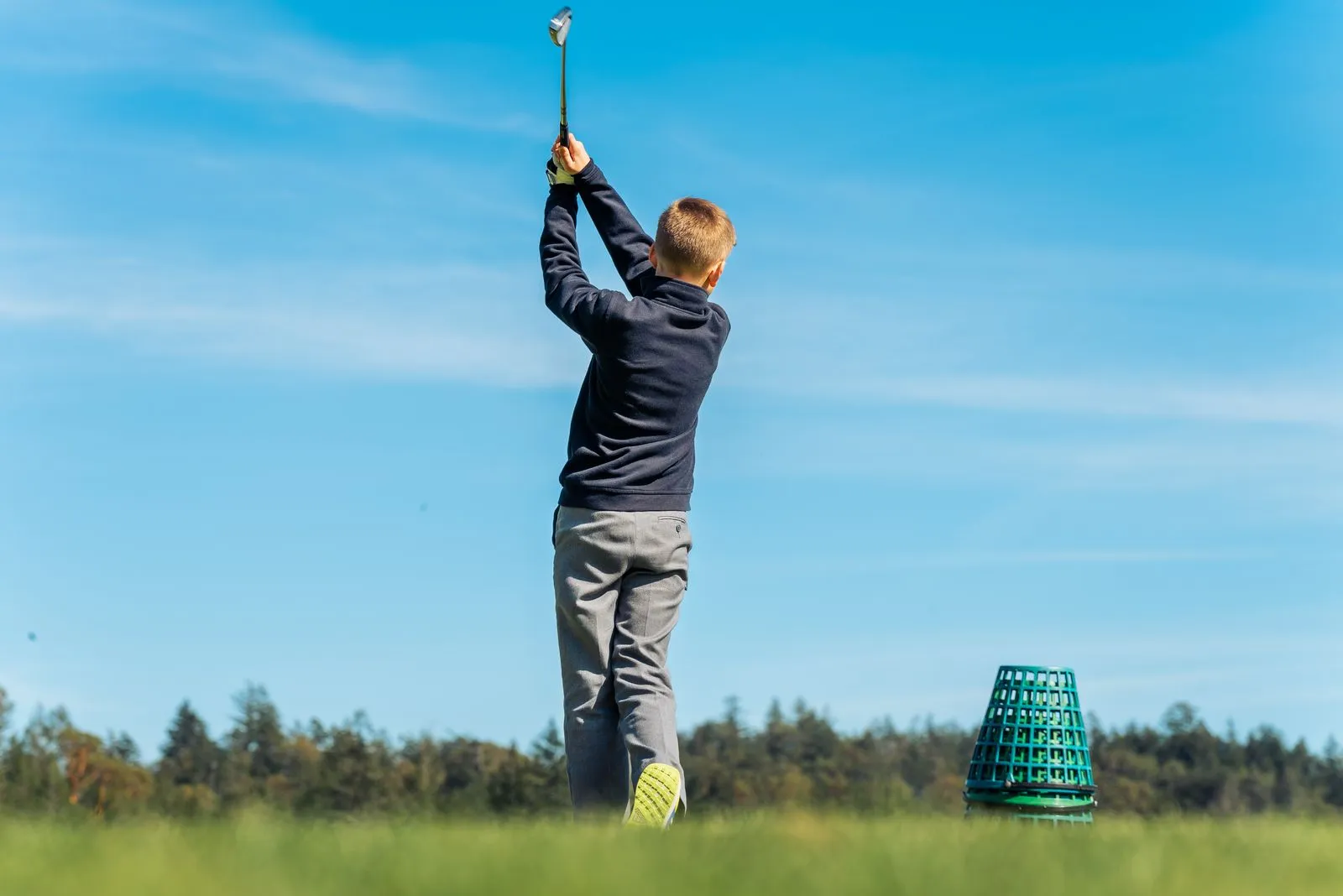 A young boy practicing his golf swing outdoors on a sunny day in Colwood, BC.